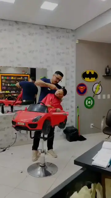 Barbeiro cortando cabelo de criança na cadeira carrinho